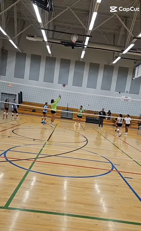 Players practicing on the court at a community volleyball camp